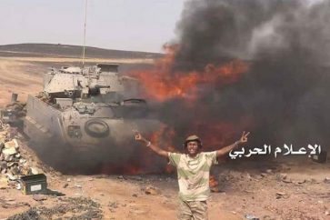 Un combattant d'Ansarullah devant un char saoudien incendié par les tirs yéménites